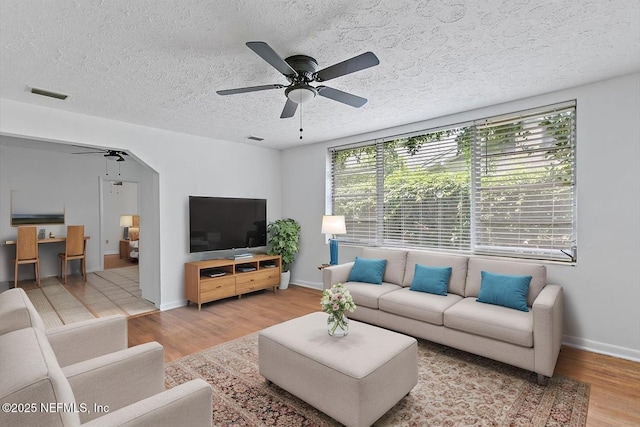living room featuring a ceiling fan, wood finished floors, a textured ceiling, and baseboards