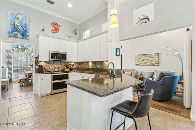 2738 Sea Grove Ln, Fernandina Beach, FL 32034 - kitchen with a sink, stainless steel microwave, a towering ceiling, a peninsula, and crown molding