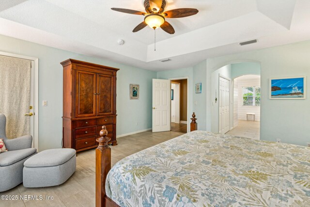 2738 Sea Grove Ln, Fernandina Beach, FL 32034 - bedroom featuring a raised ceiling, arched walkways, ensuite bath, a ceiling fan, and baseboards