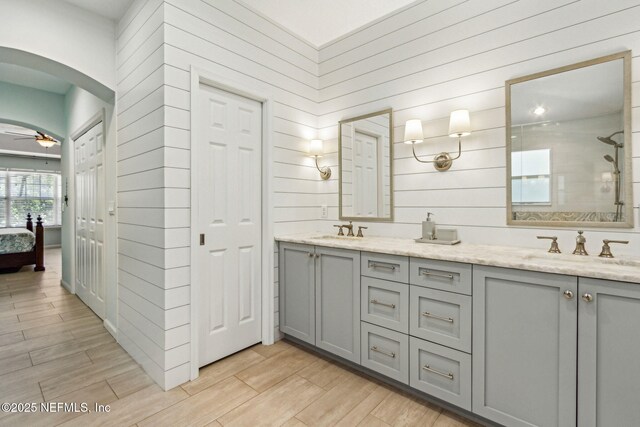 2738 Sea Grove Ln, Fernandina Beach, FL 32034 - ensuite bathroom with double vanity, wood finished floors, wooden walls, a ceiling fan, and tiled shower