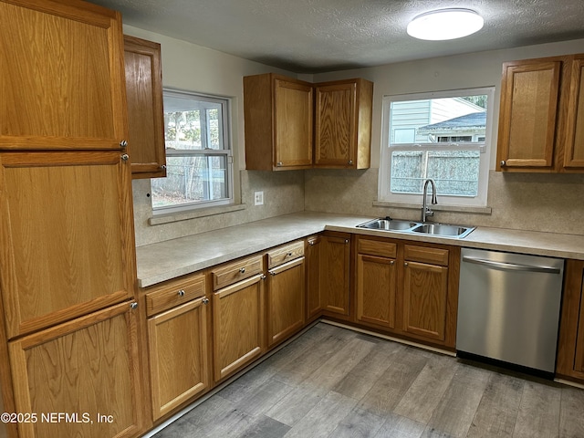 234 Canis St W, Orange Park, FL 32073 - kitchen with stainless steel dishwasher, a sink, brown cabinetry, plenty of natural light, and a textured ceiling
