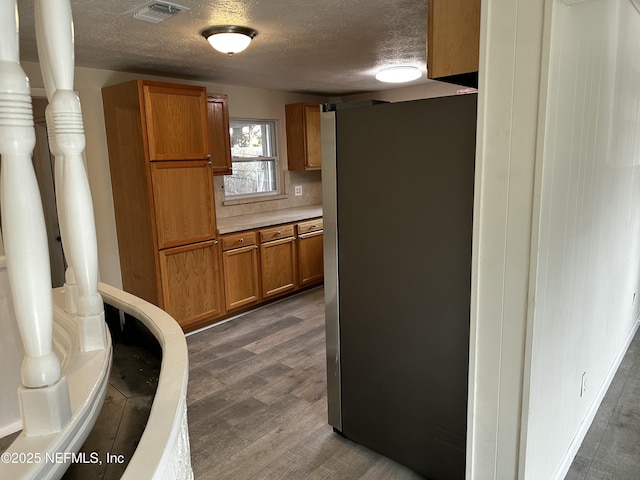 234 Canis St W, Orange Park, FL 32073 - kitchen with freestanding refrigerator, brown cabinetry, dark wood-style floors, a textured ceiling, and light countertops