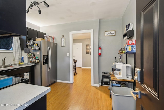 7345 Penrose St, Jacksonville, FL 32208 - kitchen featuring light wood-type flooring, dark cabinets, stainless steel fridge with ice dispenser, a sink, and light countertops