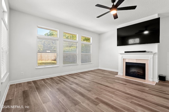 129 Lake Run Blvd, Jacksonville, FL 32218 - unfurnished living room featuring a fireplace with raised hearth, a ceiling fan, wood finished floors, a textured ceiling, and baseboards