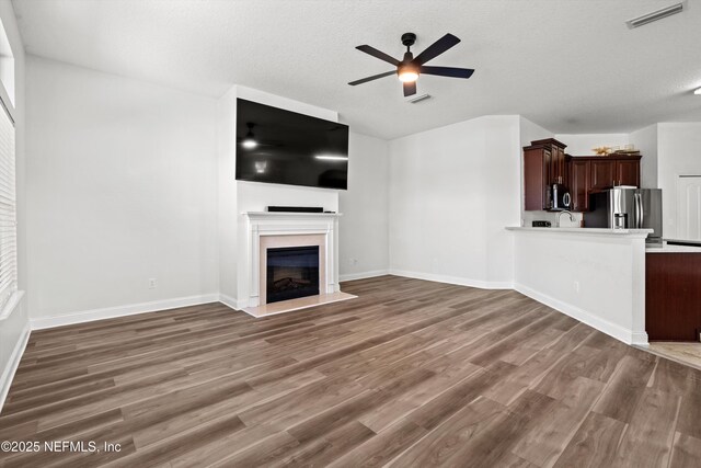 129 Lake Run Blvd, Jacksonville, FL 32218 - unfurnished living room with a ceiling fan, wood finished floors, a fireplace, a textured ceiling, and baseboards