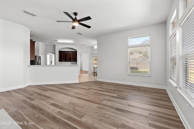 129 Lake Run Blvd, Jacksonville, FL 32218 - unfurnished living room featuring arched walkways, a ceiling fan, light wood finished floors, baseboards, and a textured ceiling
