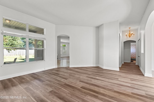 129 Lake Run Blvd, Jacksonville, FL 32218 - unfurnished living room with arched walkways, wood finished floors, a chandelier, and baseboards