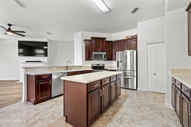 129 Lake Run Blvd, Jacksonville, FL 32218 - kitchen with stainless steel appliances, a peninsula, light countertops, ceiling fan, and a kitchen island
