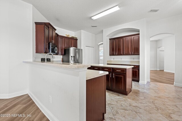 129 Lake Run Blvd, Jacksonville, FL 32218 - kitchen with stainless steel appliances, arched walkways, light countertops, a peninsula, and a textured ceiling