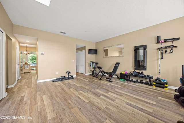 97054 Huntington Ct, Yulee, FL 32097 - workout room with light wood-type flooring, a chandelier, and baseboards