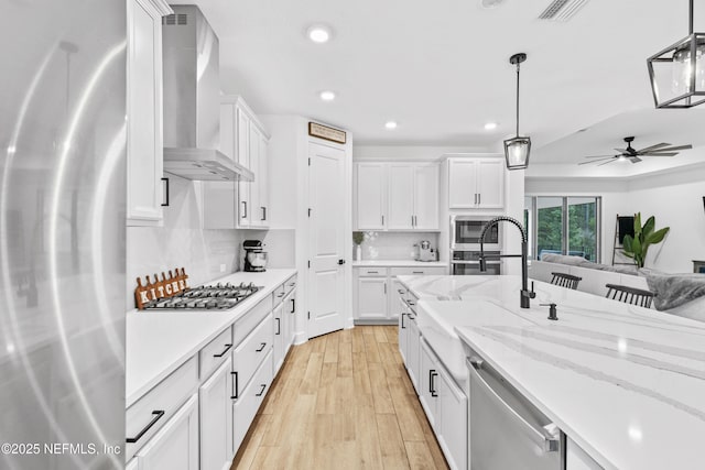 166 Spinner Dr, Ponte Vedra, FL 32081 - kitchen with stainless steel appliances, wall chimney exhaust hood, a sink, recessed lighting, and white cabinetry