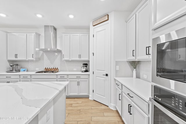 166 Spinner Dr, Ponte Vedra, FL 32081 - kitchen featuring appliances with stainless steel finishes, wall chimney exhaust hood, white cabinetry, light wood-type flooring, and recessed lighting