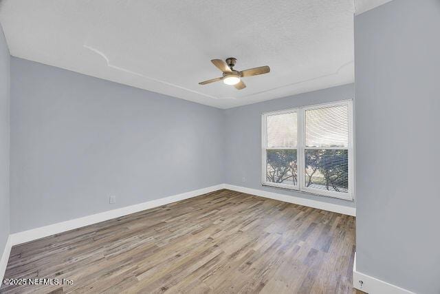 spare room with baseboards, wood finished floors, and ceiling fan