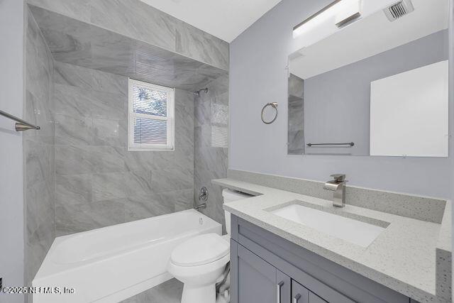 bathroom featuring vanity, toilet, and shower / bathtub combination