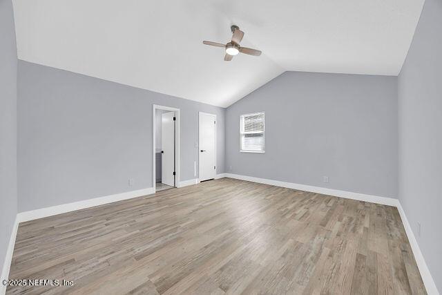 unfurnished bedroom featuring lofted ceiling, wood finished floors, baseboards, and a ceiling fan