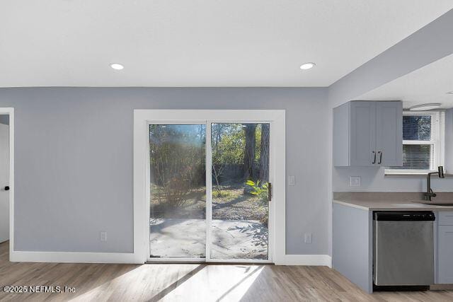 kitchen with dishwasher, light wood-type flooring, baseboards, gray cabinets, and a sink