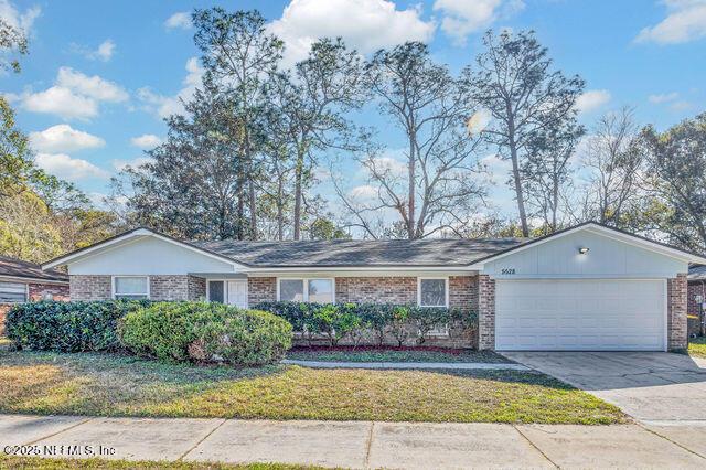 ranch-style house with brick siding, a garage, concrete driveway, and a front lawn