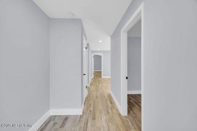 corridor with light wood-style flooring, baseboards, and recessed lighting