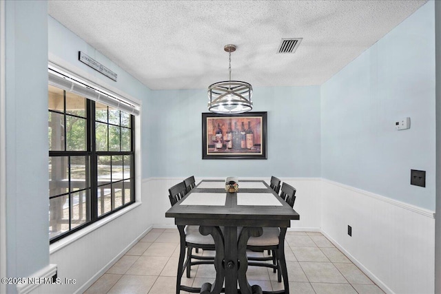 4310 Chokeberry Rd, Middleburg, FL 32068 - dining area featuring a textured ceiling, wainscoting, a chandelier, and light tile patterned floors