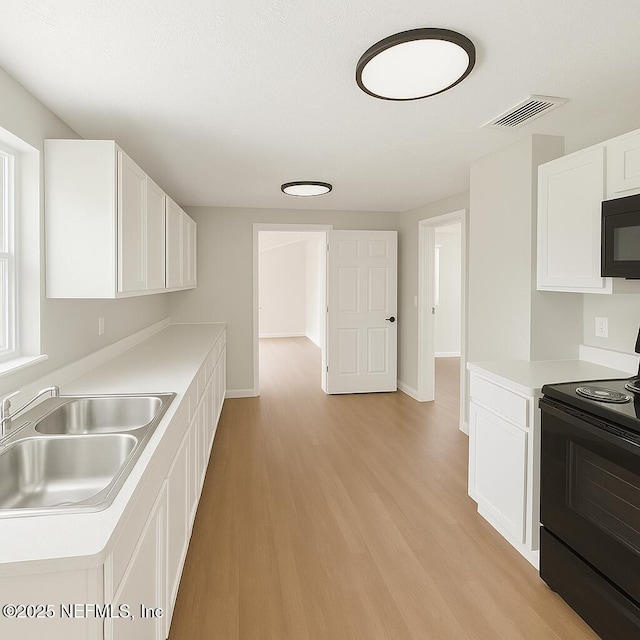 1109 Lake Shore Blvd, Jacksonville, FL 32205 - kitchen featuring black appliances, a sink, light countertops, white cabinets, and light wood-style flooring