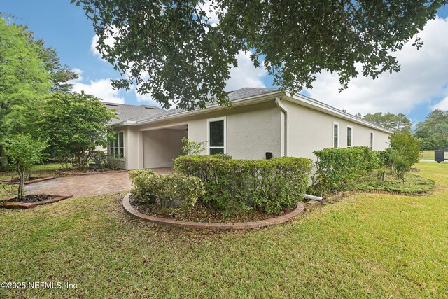 124 Medio Dr, Saint Augustine, FL 32095 - view of side of home featuring a patio, stucco siding, a yard, and decorative driveway