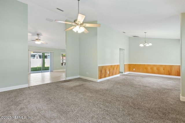 carpeted spare room with vaulted ceiling, a chandelier, ceiling fan, and baseboards