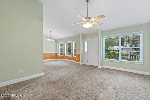 unfurnished living room featuring a chandelier, ceiling fan, carpet floors, baseboards, and lofted ceiling