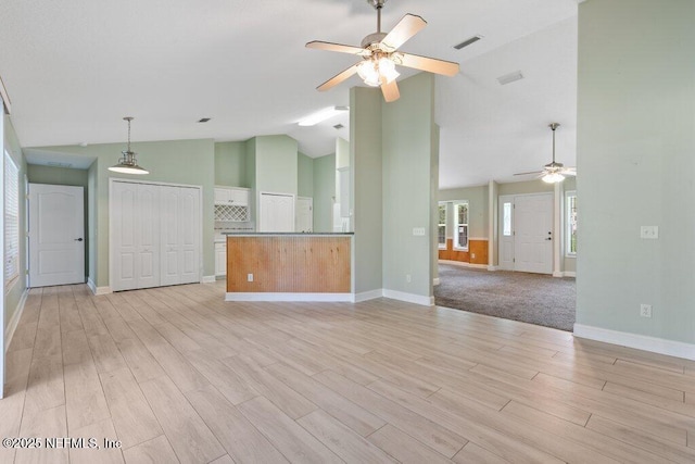 unfurnished living room featuring ceiling fan, light wood finished floors, high vaulted ceiling, and baseboards