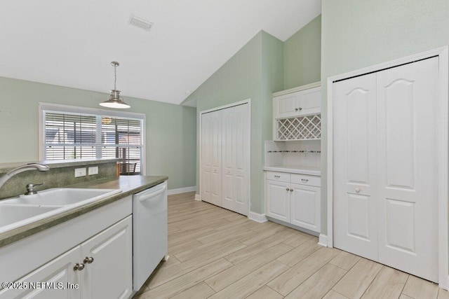 kitchen with dishwasher, lofted ceiling, white cabinets, pendant lighting, and light wood-type flooring