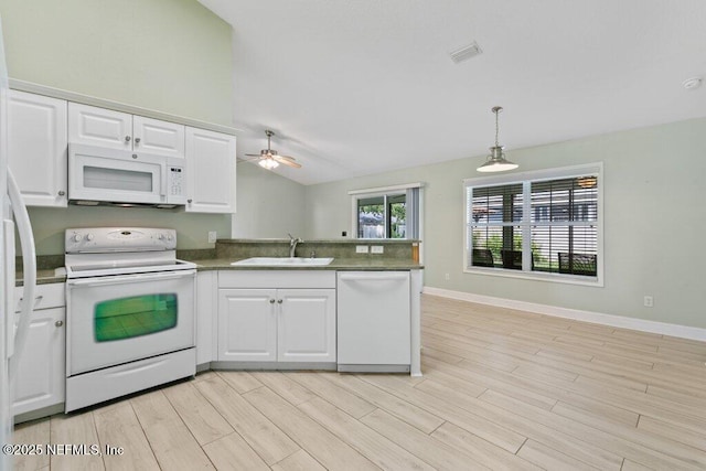 kitchen featuring white appliances, a peninsula, a sink, white cabinetry, and lofted ceiling