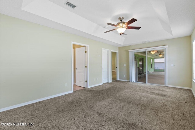 unfurnished bedroom featuring a raised ceiling, carpet floors, baseboards, and ceiling fan