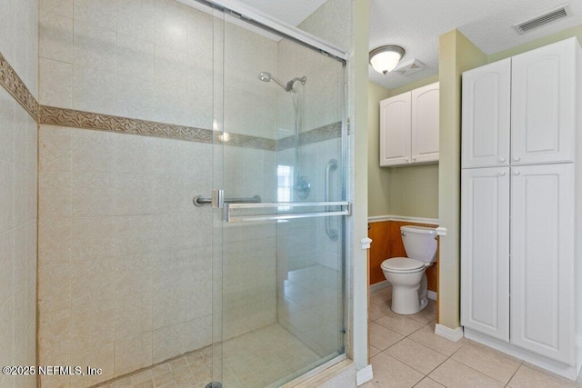 bathroom featuring tile patterned floors, a stall shower, toilet, and a textured ceiling