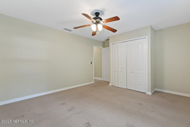 unfurnished bedroom with carpet flooring, baseboards, a closet, and a ceiling fan