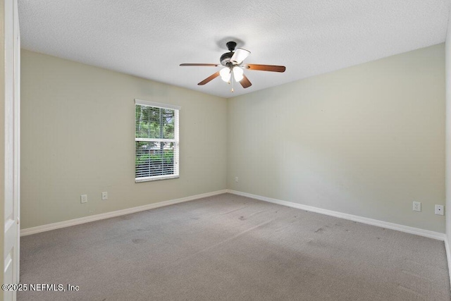carpeted spare room with ceiling fan, baseboards, and a textured ceiling