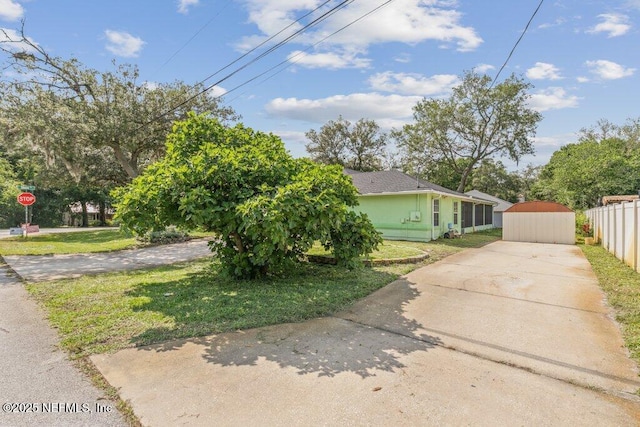 view of front of property with concrete driveway, a storage shed, stucco siding, and an outbuilding