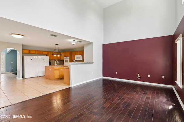 76466 Long Leaf Loop, Yulee, FL 32097 - unfurnished living room with arched walkways, light wood-style floors, a sink, a high ceiling, and baseboards