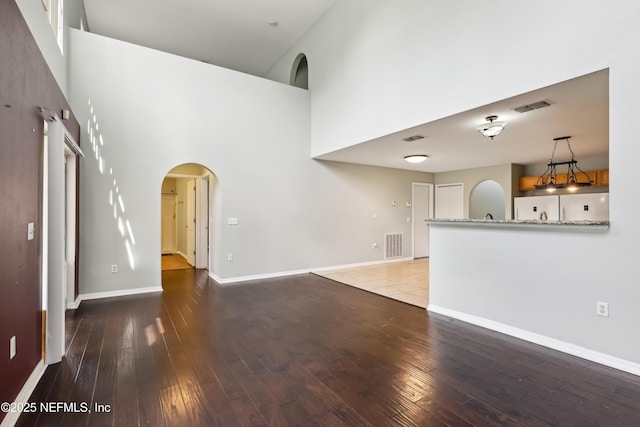 76466 Long Leaf Loop, Yulee, FL 32097 - unfurnished living room featuring a towering ceiling, arched walkways, hardwood / wood-style floors, and baseboards