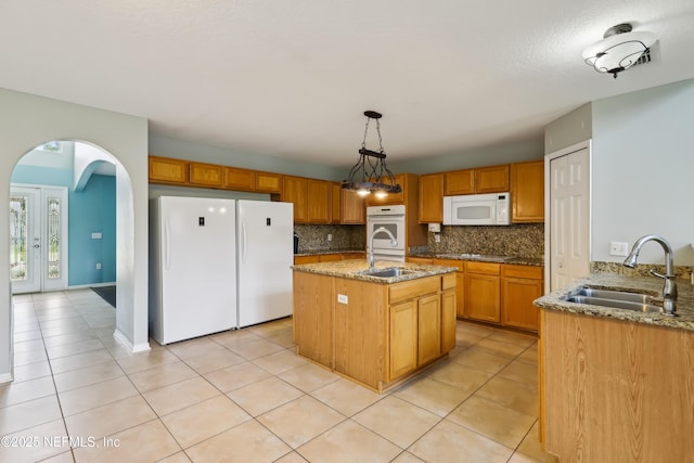 76466 Long Leaf Loop, Yulee, FL 32097 - kitchen with white appliances, a sink, decorative backsplash, arched walkways, and light stone countertops