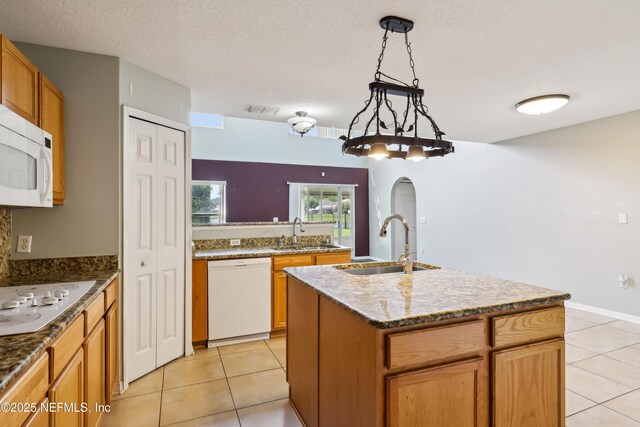 76466 Long Leaf Loop, Yulee, FL 32097 - kitchen with white appliances, a sink, light tile patterned floors, an island with sink, and a textured ceiling