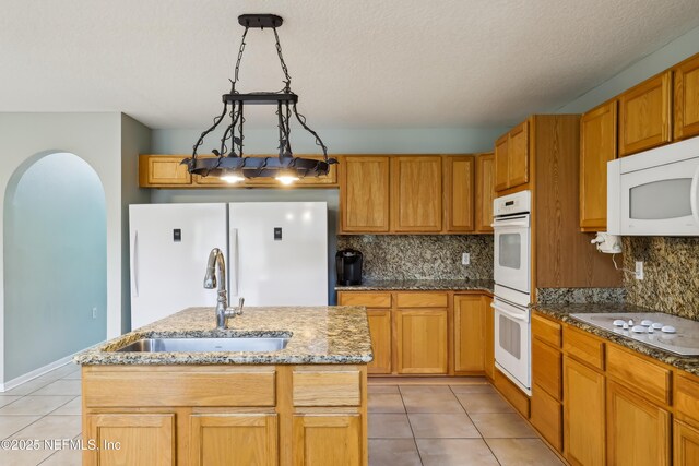 76466 Long Leaf Loop, Yulee, FL 32097 - kitchen featuring white appliances, a sink, light tile patterned floors, tasteful backsplash, and a kitchen island with sink