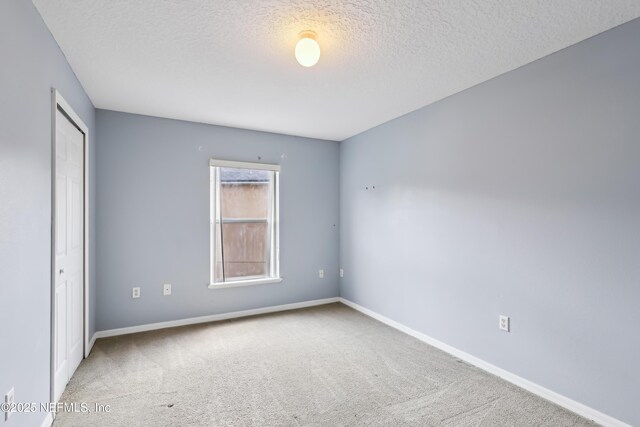 76466 Long Leaf Loop, Yulee, FL 32097 - unfurnished bedroom featuring carpet floors, a textured ceiling, baseboards, and a closet