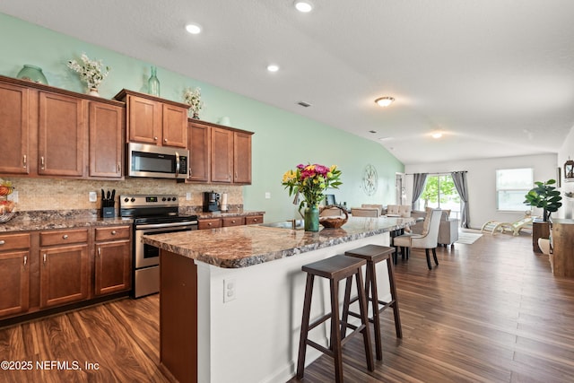 2840 Buck Creek Pl, Green Cove Springs, FL 32043 - kitchen featuring appliances with stainless steel finishes, dark wood-style floors, backsplash, a breakfast bar, and a center island with sink