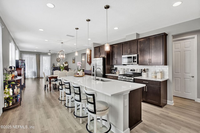 267 Honeycomb Trl, Saint Augustine, FL 32095 - kitchen with stainless steel appliances, a sink, dark brown cabinets, a breakfast bar, and light wood-type flooring