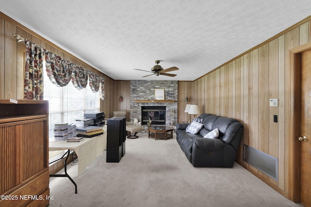 359 Carson Dr, Orange Park, FL 32073 - carpeted living room with a ceiling fan, a textured ceiling, a fireplace, wood walls, and crown molding