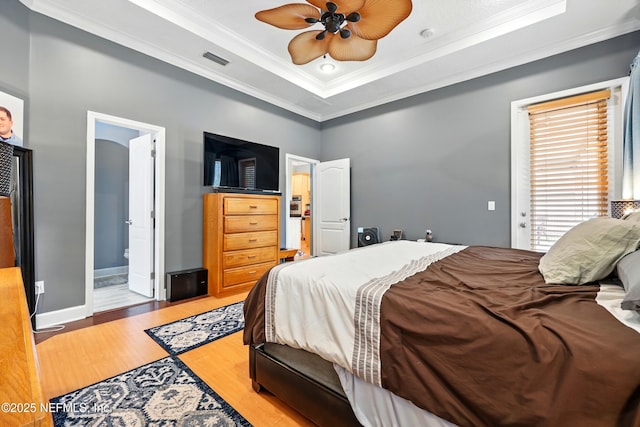 85053 Sagaponack Dr, Fernandina Beach, FL 32034 - bedroom featuring ornamental molding, a tray ceiling, light wood-type flooring, baseboards, and ensuite bathroom