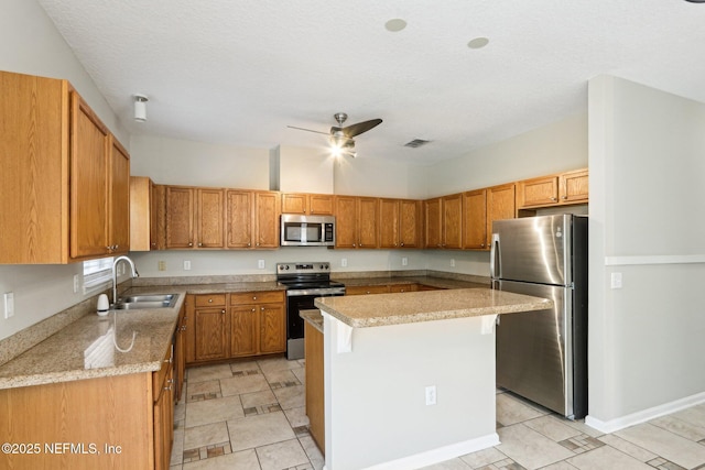 2454 Woodstork Ct, Saint Augustine, FL 32092 - kitchen with appliances with stainless steel finishes, a sink, a kitchen island, ceiling fan, and brown cabinetry