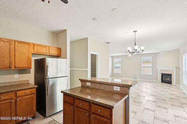 2454 Woodstork Ct, Saint Augustine, FL 32092 - kitchen featuring freestanding refrigerator, a chandelier, a center island, a ceiling fan, and dark stone counters