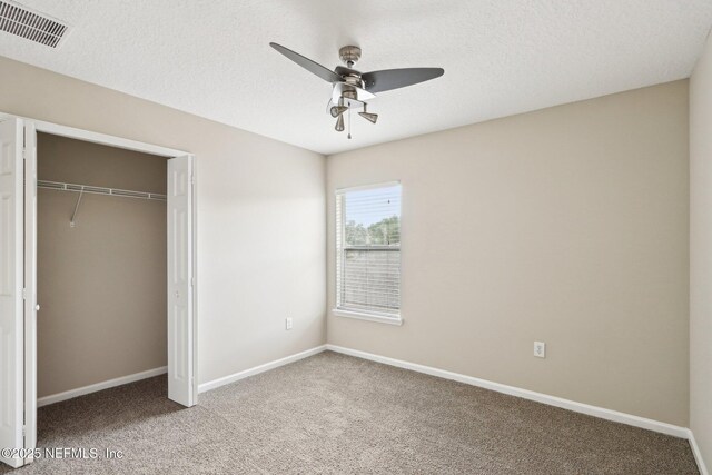 2454 Woodstork Ct, Saint Augustine, FL 32092 - unfurnished bedroom featuring carpet floors, baseboards, a closet, a ceiling fan, and a textured ceiling