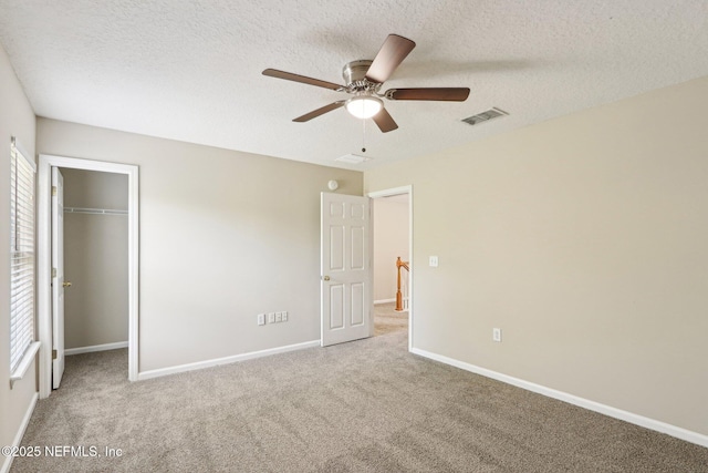2454 Woodstork Ct, Saint Augustine, FL 32092 - unfurnished bedroom featuring carpet floors, a textured ceiling, baseboards, a walk in closet, and a closet