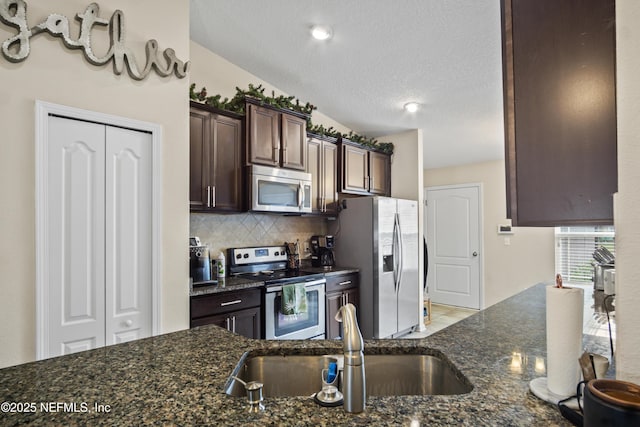 15831 Baxter Creek Dr, Jacksonville, FL 32218 - kitchen featuring stainless steel appliances, a sink, dark brown cabinetry, decorative backsplash, and a textured ceiling